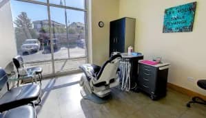 A treatment room with a patient chair and large windows